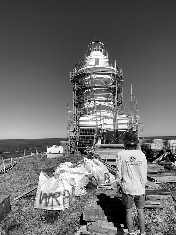 A Man is Standing in Front of a Lighthouse Under Construction — RM Scaffolding Solutions in Lennox Head, NSW