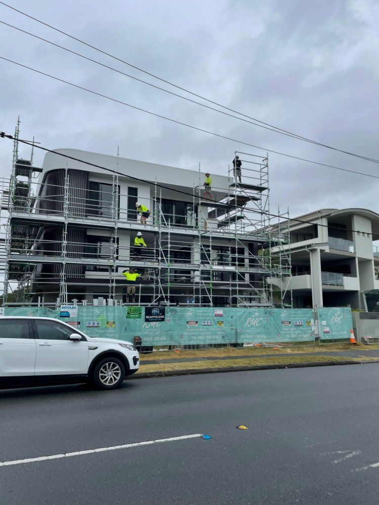 A White Car is Parked in Front of a Building Under Construction — RM Scaffolding Solutions in Lennox Head, NSW