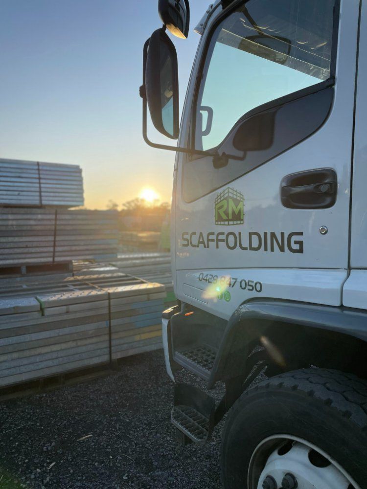A White Scaffolding Truck is Parked in Front of a Pile of Scaffolding — RM Scaffolding Solutions in Lennox Head, NSW