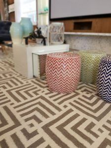 Uma sala de estar com tapete, pufes e televisão.