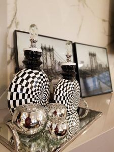 Um vaso xadrez preto e branco está em cima de uma bandeja espelhada.