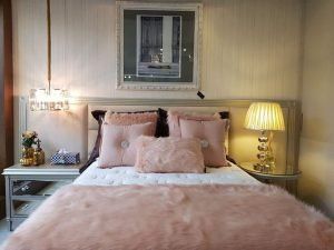 Um quarto com cama, mesa de cabeceira, abajur e quadro na parede.