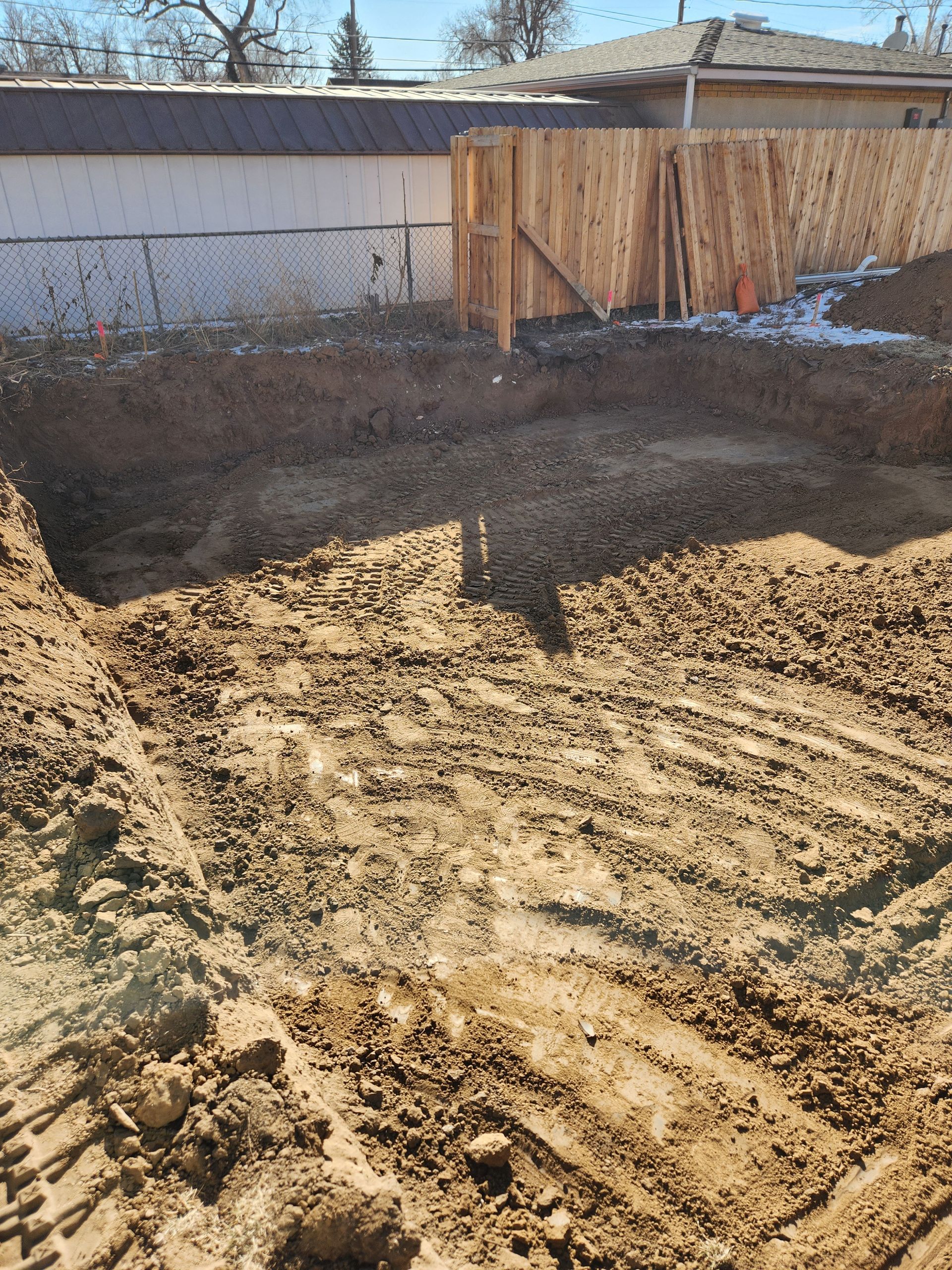 A yellow excavator digging a trench in a field under a clear blue sky.