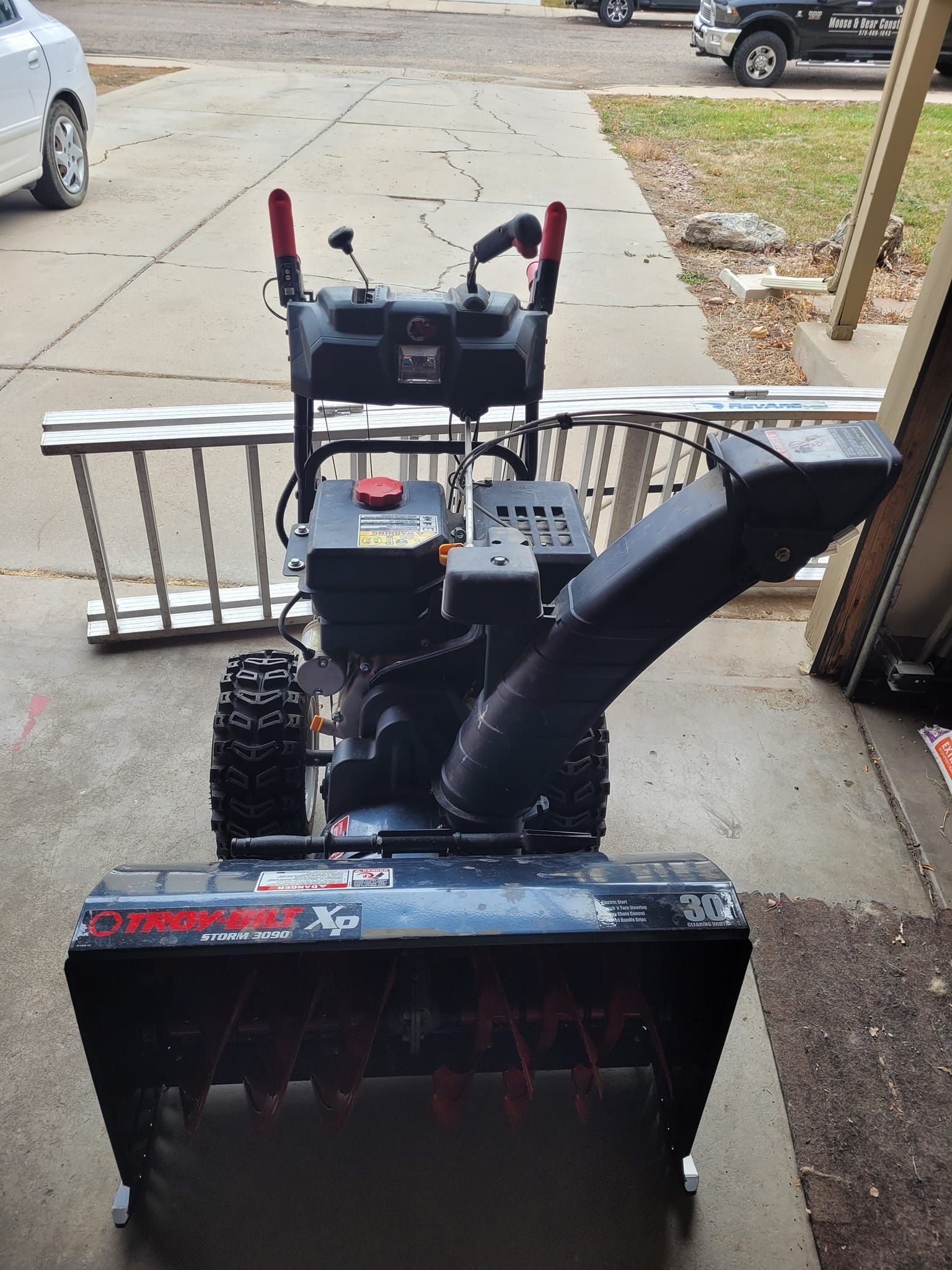 Snow blower on a driveway, black with red accents.