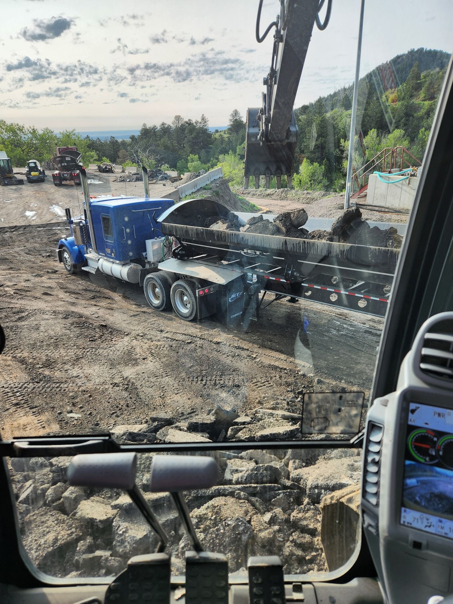 Excavator loading dirt into a blue dump truck at a construction site.