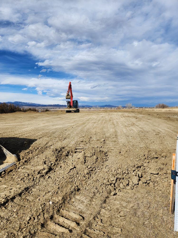 An excavator on a dirt construction site under a cloudy sky.