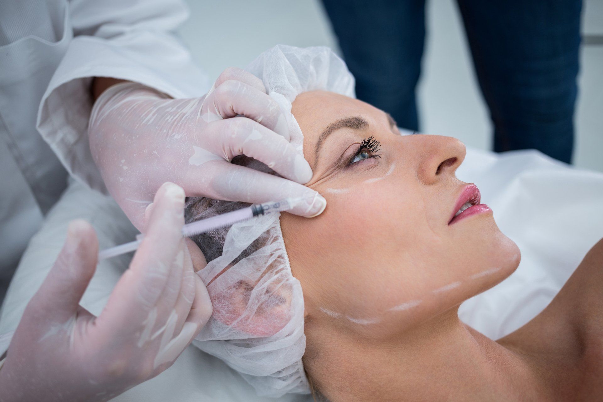 A woman is getting a botox injection in her face.