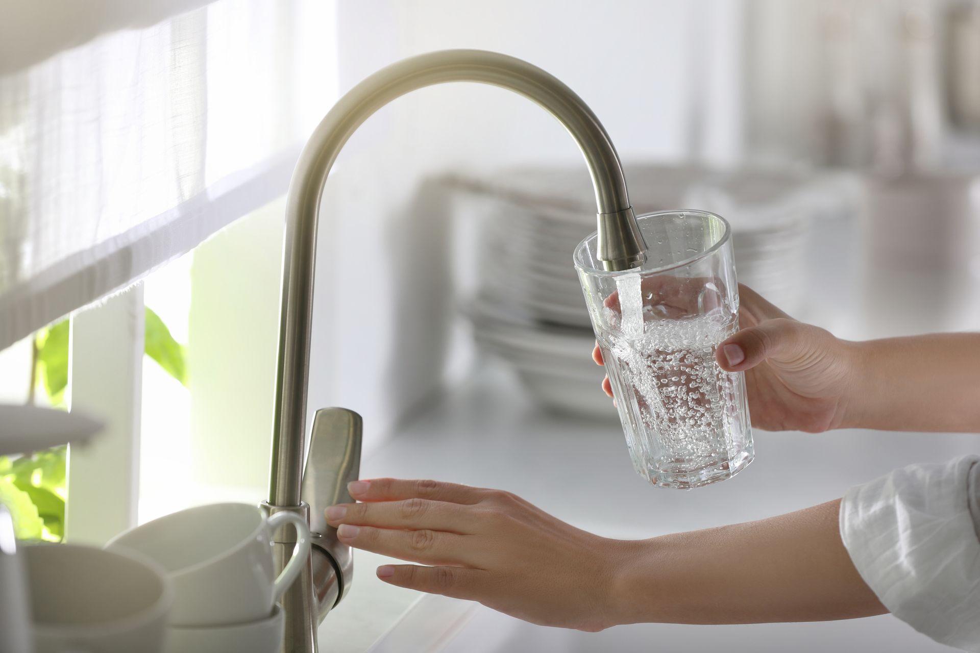 A woman in Virginia getting water from the tap in a clear glass.