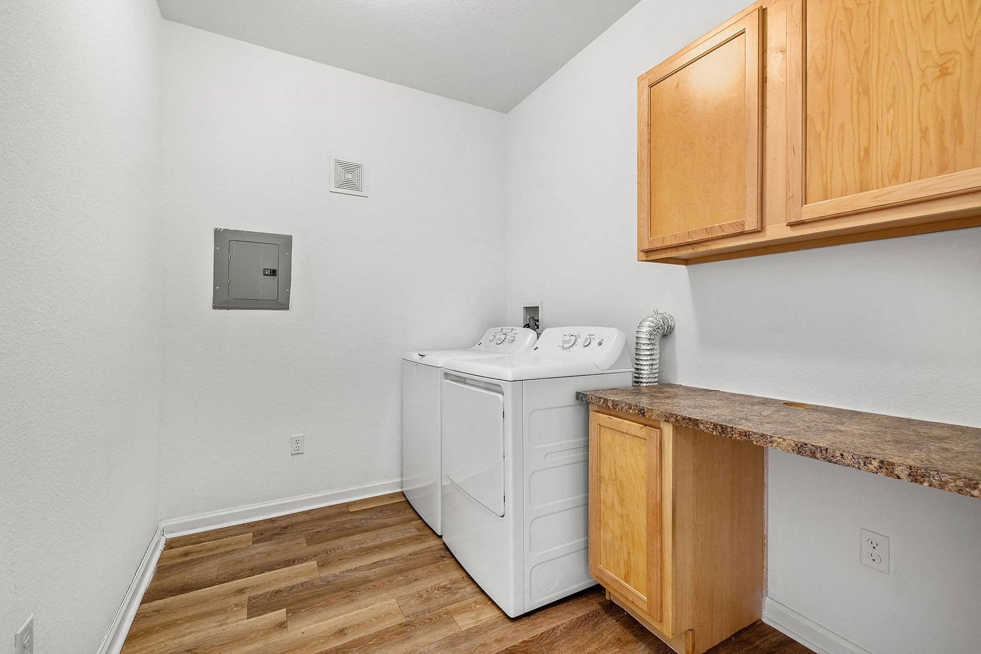 Laundry room with a top-load washer and dryer, wooden cabinets, and a laminate countertop.