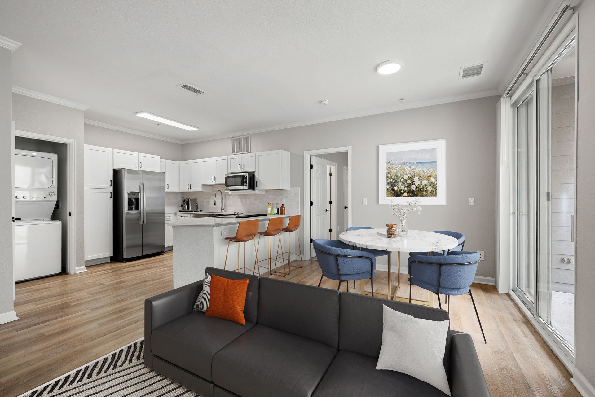 Open-concept living area with white cabinets, stainless appliances, an island, and a round dining table.