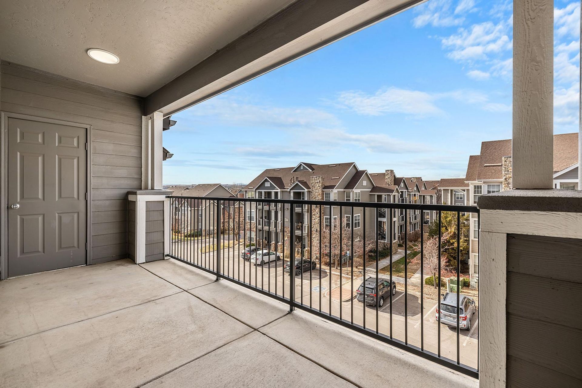 Balcony view of a multi-building apartment complex with a parking lot below.