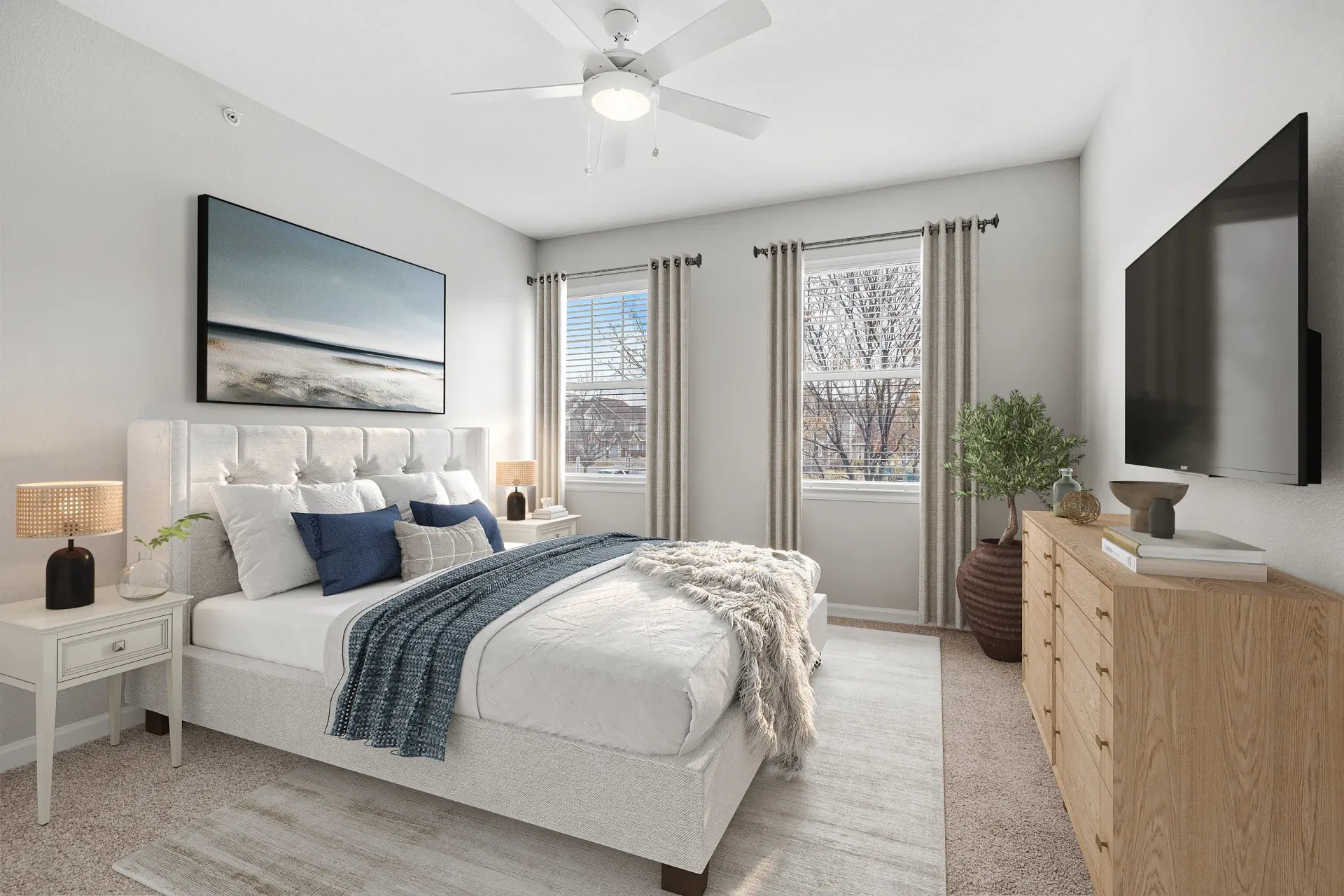 Bedroom in an apartment with a tufted headboard, two nightstands, a dresser, and a large window.