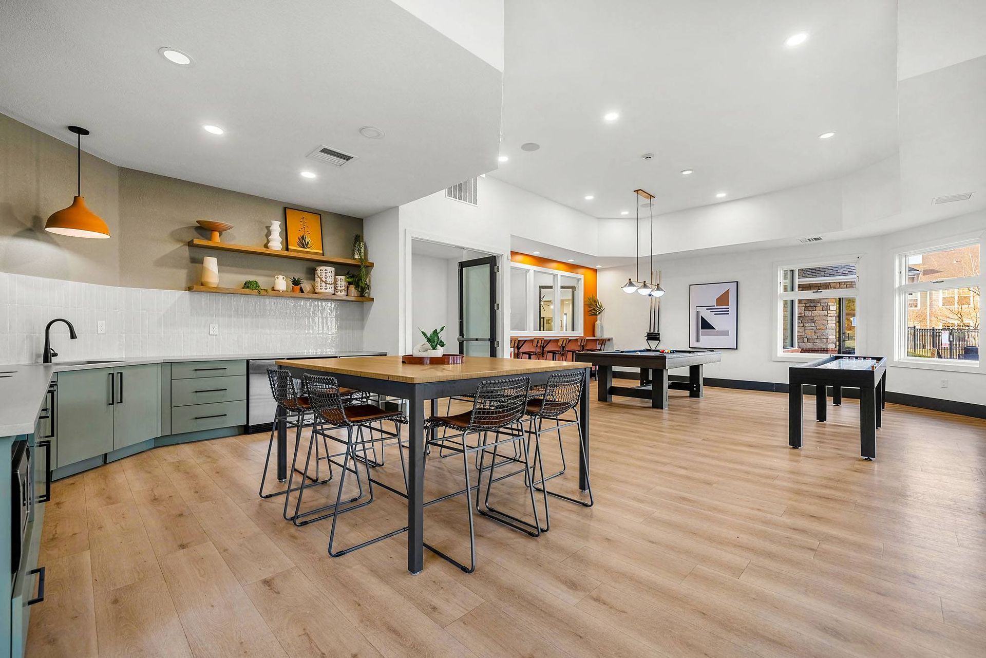 Bright community lounge with a kitchen island, seating, and a pool table area.