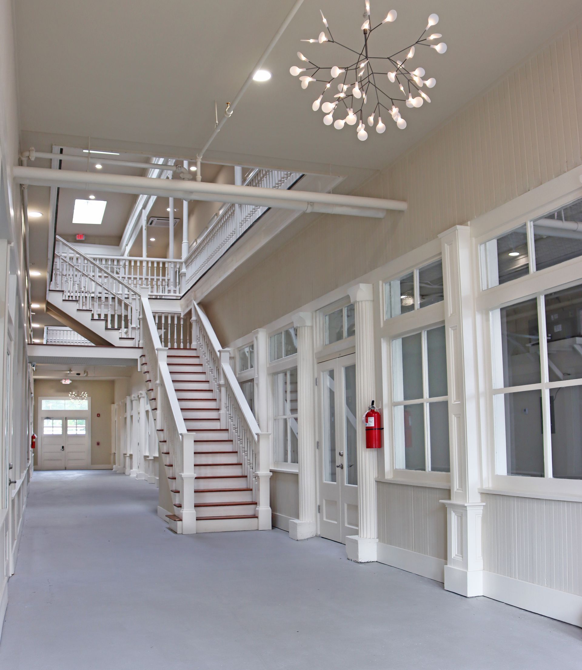 A hallway with stairs and a red fire extinguisher