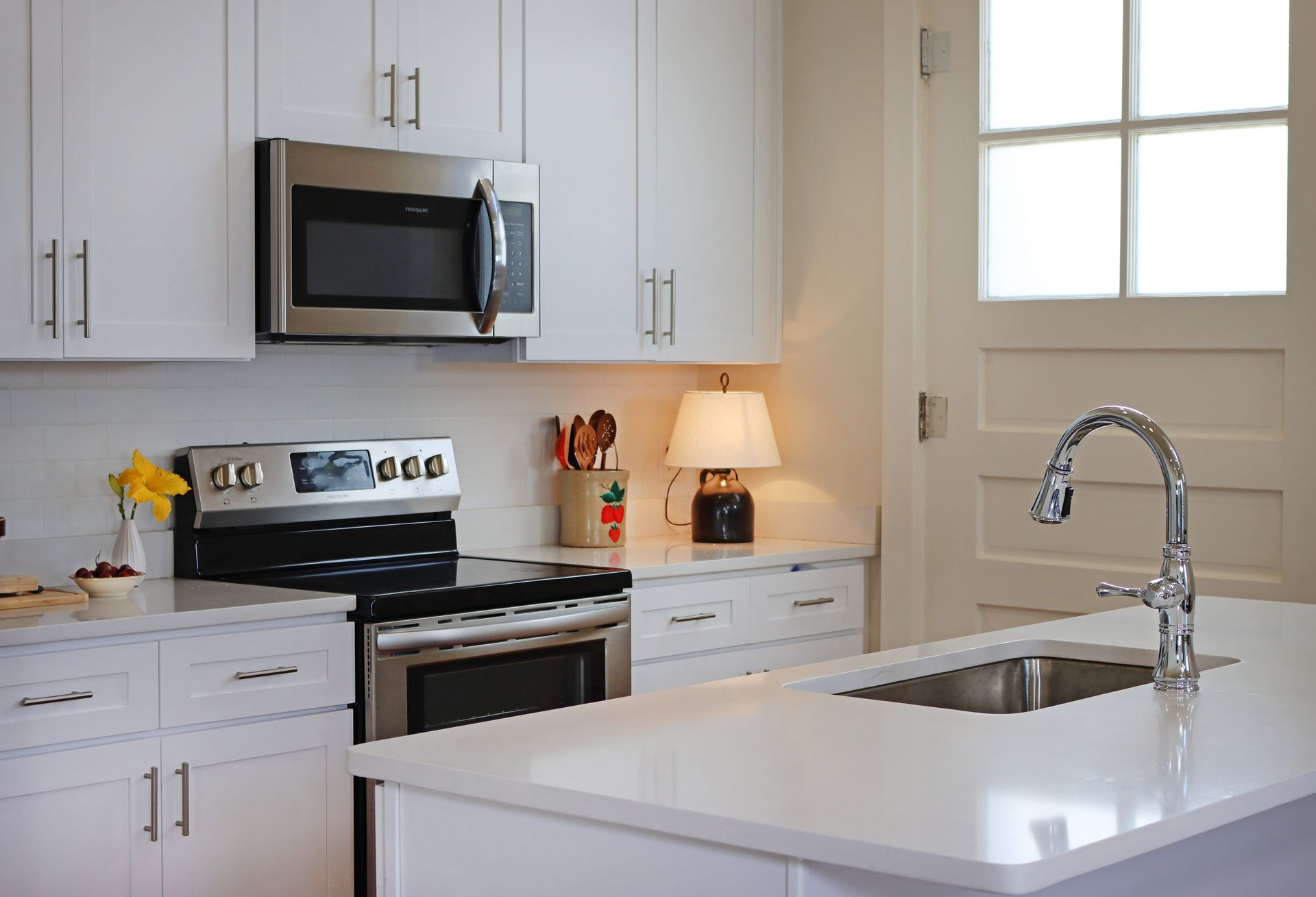 A kitchen with white cabinets stainless steel appliances and a sink