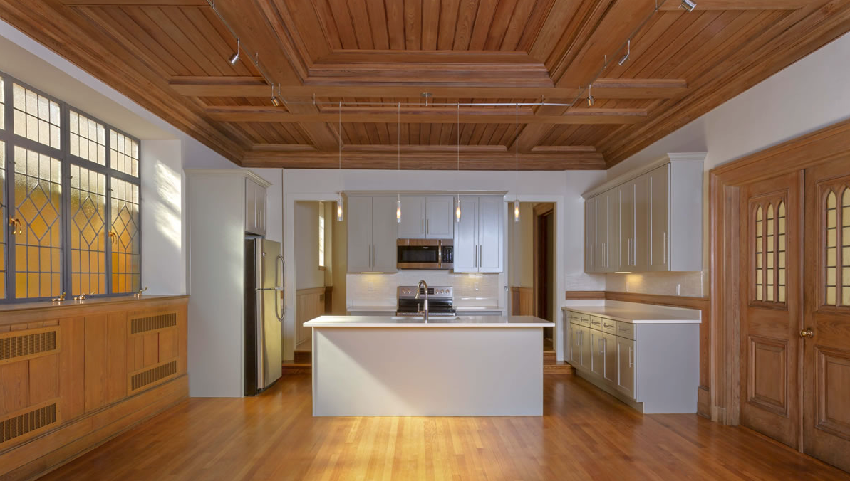 An empty kitchen with a wooden ceiling and hardwood floors.