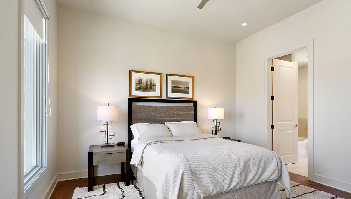 A bedroom with a bed , nightstand , lamps and a ceiling fan.