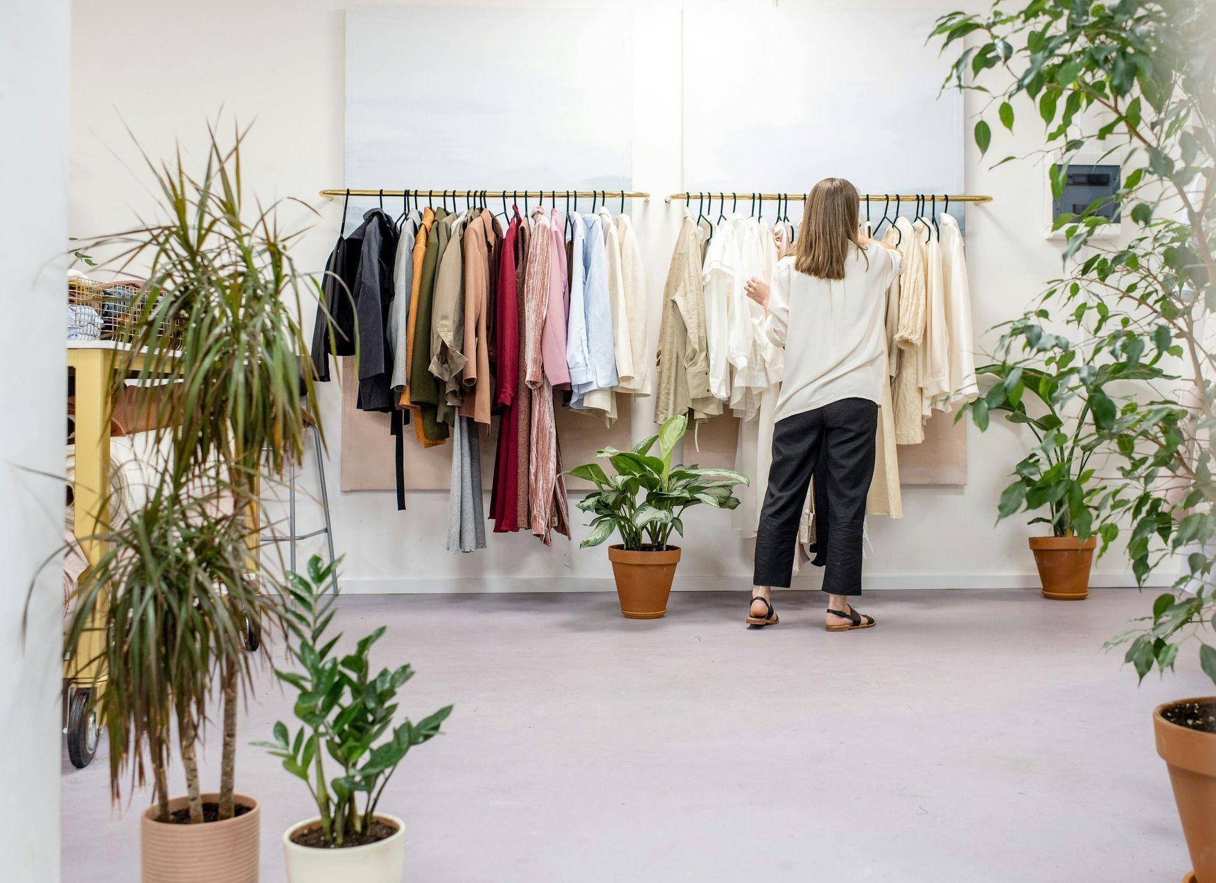 A woman is standing in front of a clothes rack in a store.