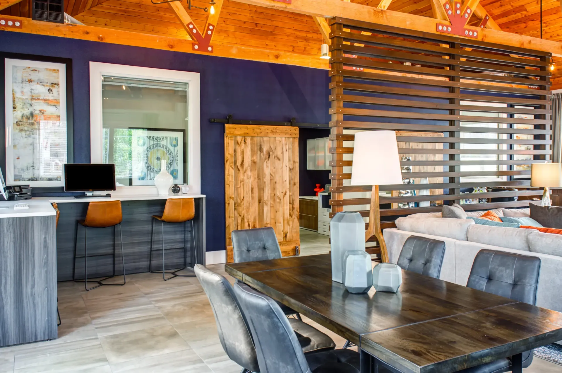 Modern interior: dining table, living area with sofa, desk, wood accents, and a blue wall.