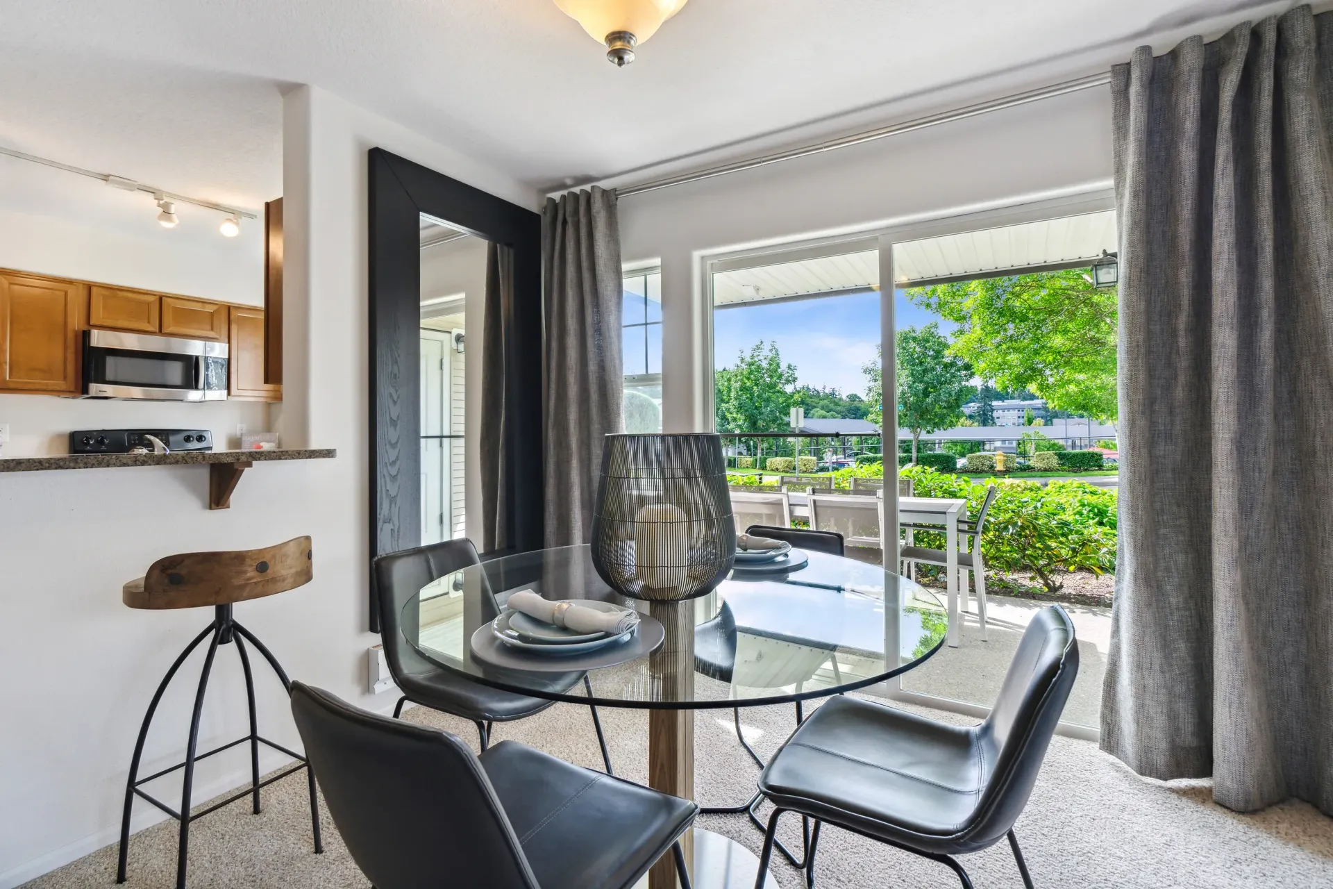 Dining area with a round glass table, black chairs, and sliding doors to a patio.