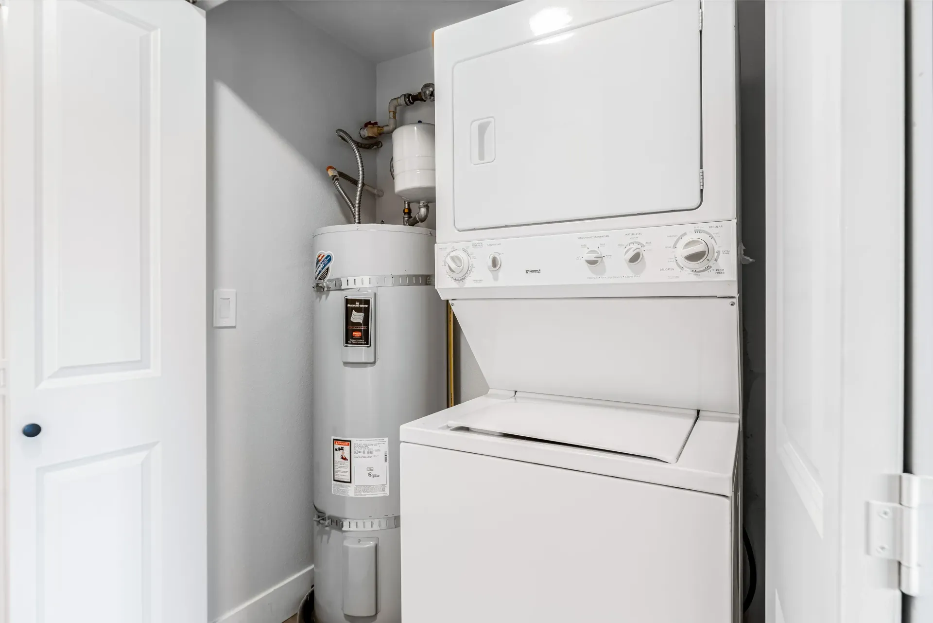 Closet with stacked washer and dryer next to a water heater.