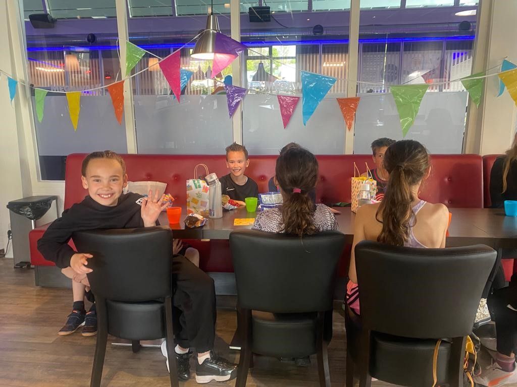 Een groep kinderen zit aan een tafel in een restaurant.