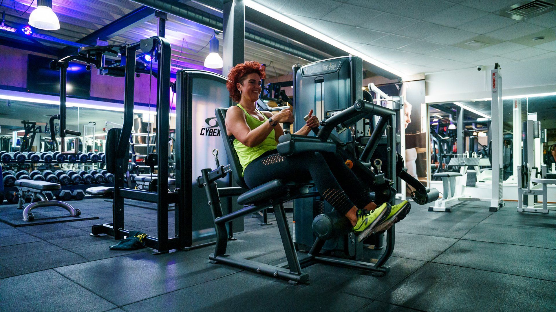 Een vrouw zit op een machine in een sportschool.