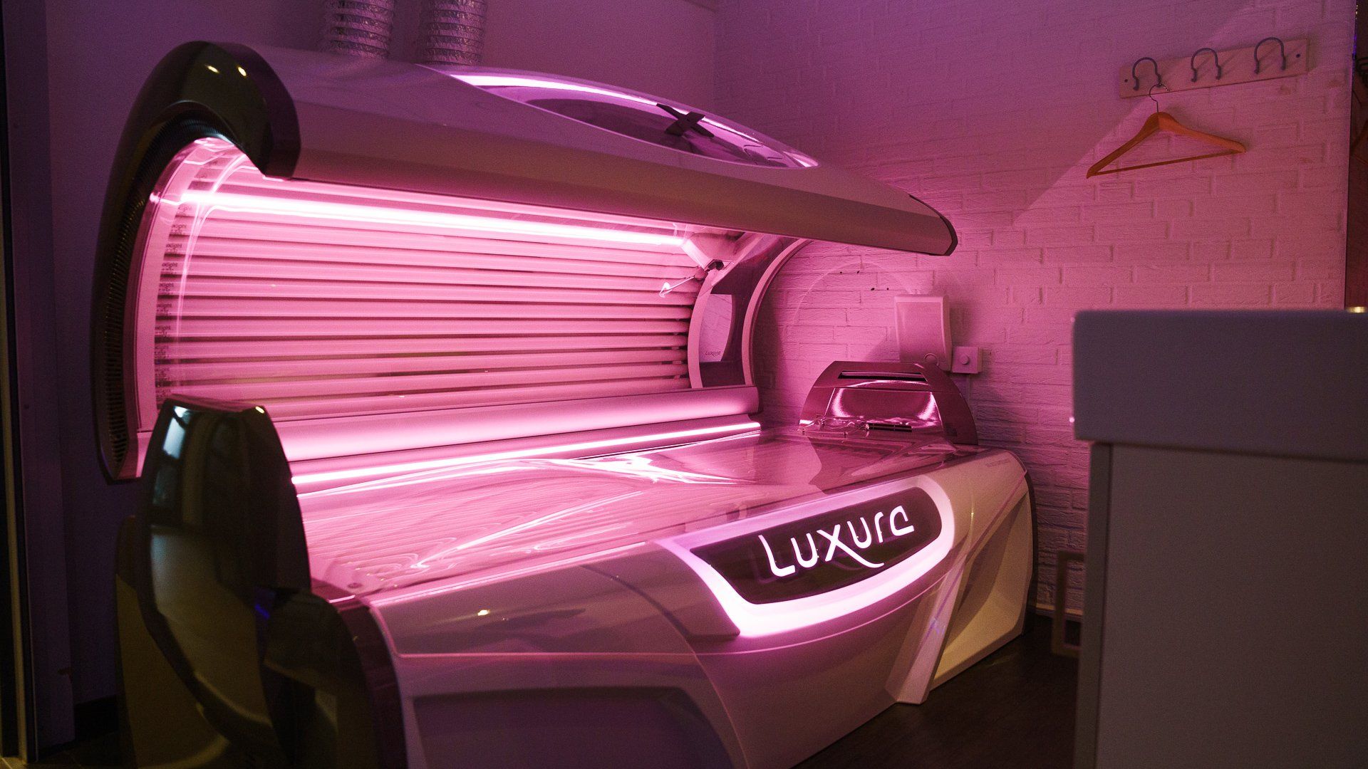 In een kamer met paarse lampen staat een zonnebank.