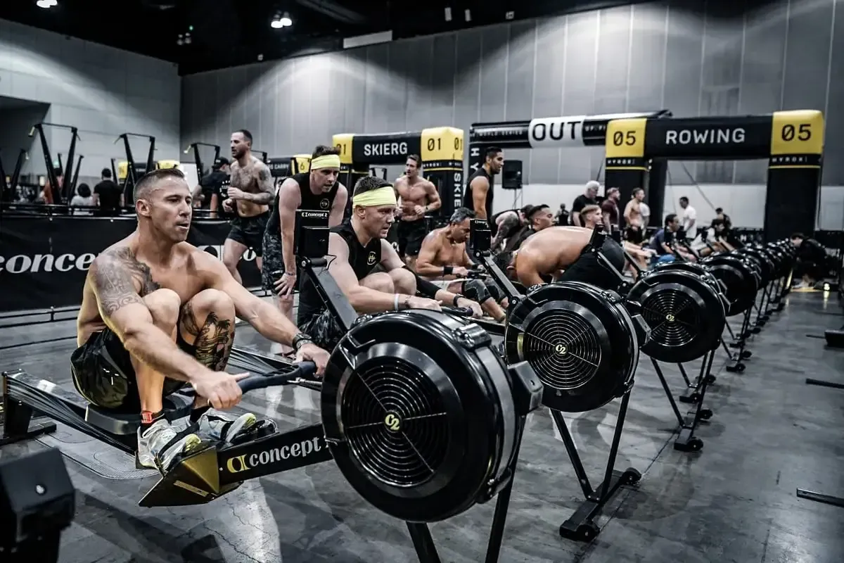 Een groep mannen roeit op roeimachines in een sportschool.