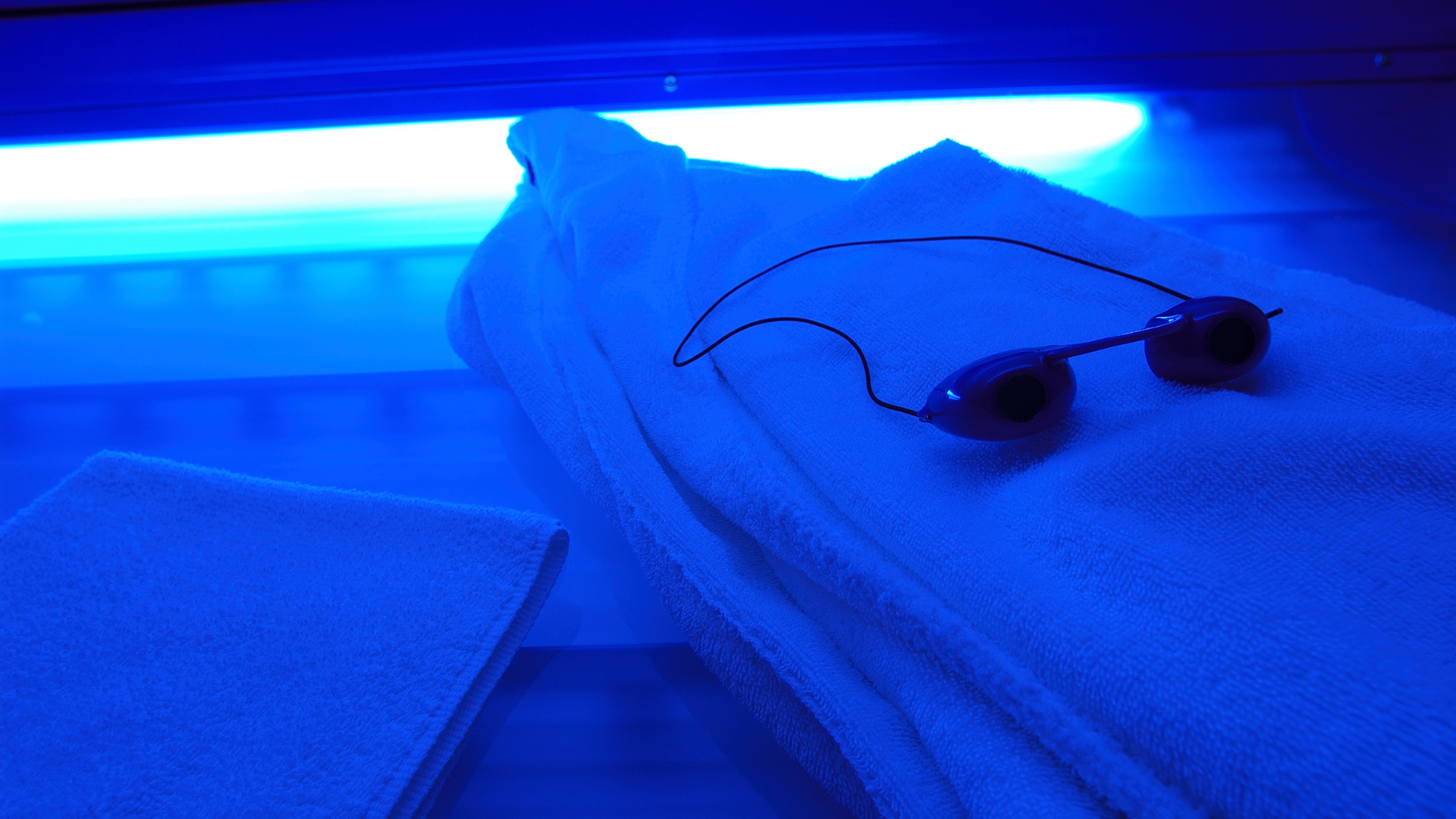 Een zonnebril zittend op een handdoek onder een blauw licht.