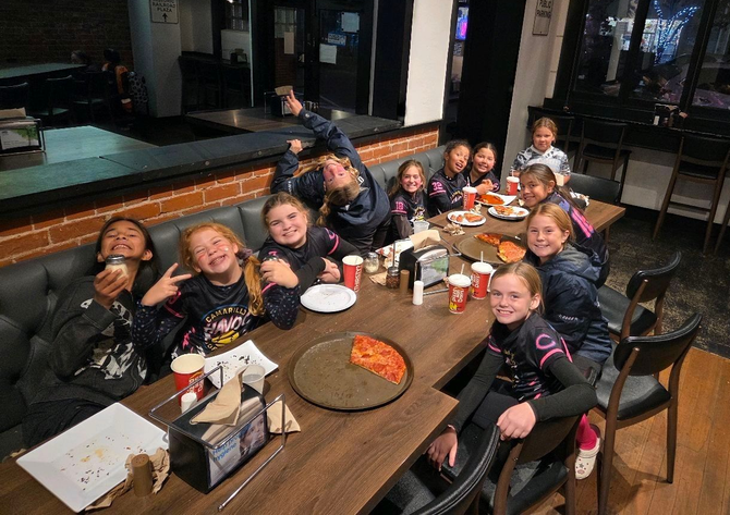 Youth softball team poses on the field, wearing uniforms.