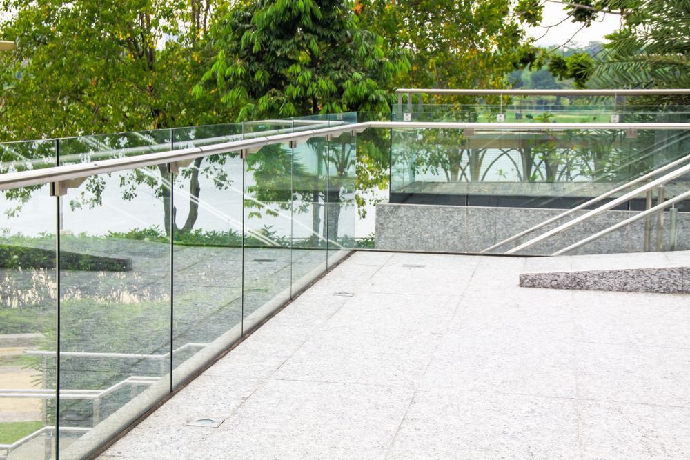 A Balcony With a Glass Railing and Trees in the Background — Top Shelf Glass Pool Fencing & Balustrading in Beenleigh, QLD
