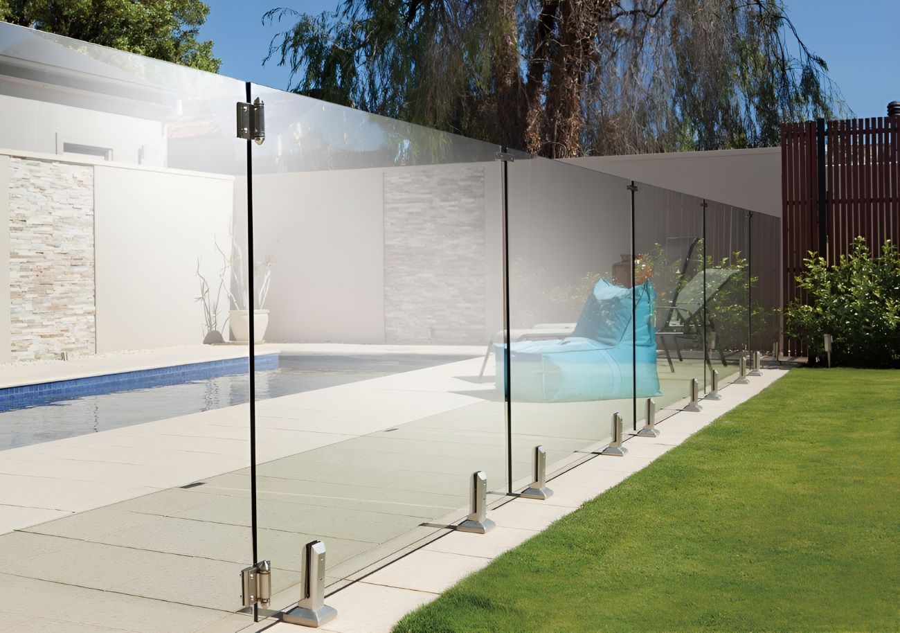 A Glass Fence Surrounds a Swimming Pool in a Backyard — Top Shelf Glass Pool Fencing & Balustrading in Merrimac, QLD