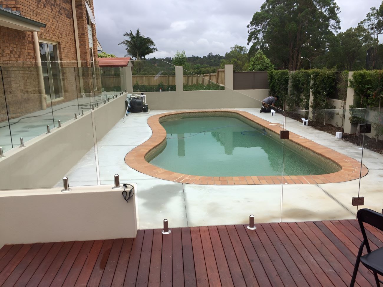 A Large Swimming Pool With a Glass Fence at the Front of House — Top Shelf Glass Pool Fencing & Balustrading in Merrimac, QLD