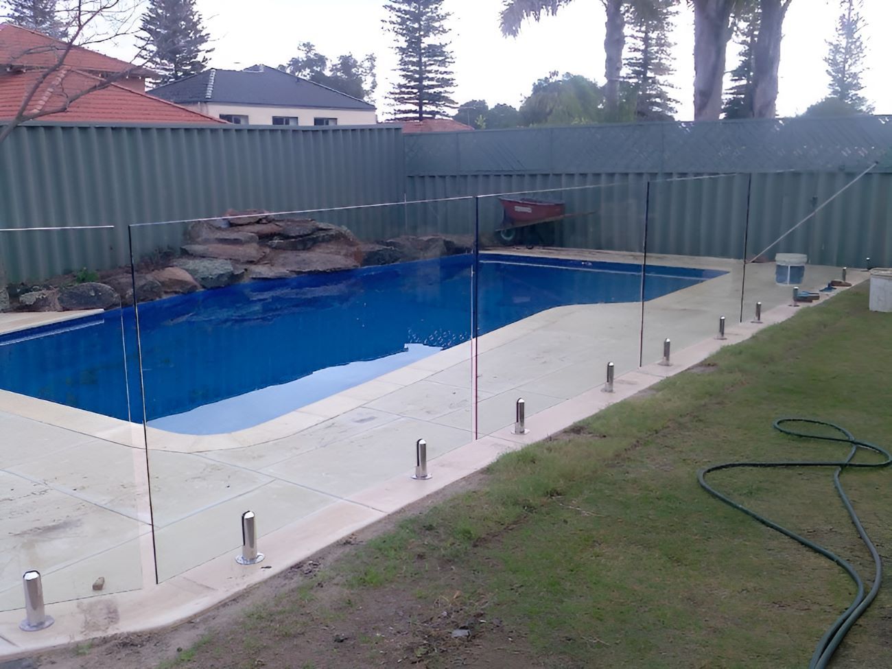A Large Swimming Pool With a Glass Fence in the Backyard — Top Shelf Glass Pool Fencing & Balustrading in Merrimac, QLD