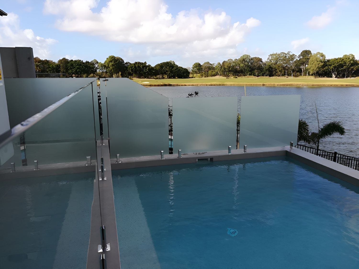 A Swimming Pool With a Glass Fence — Top Shelf Glass Pool Fencing & Balustrading in Merrimac, QLD