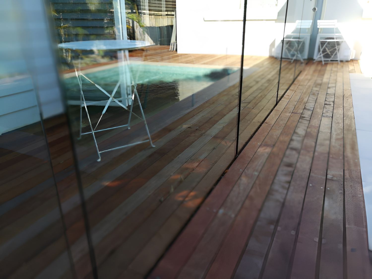 A Wooden Deck With a Table and Chairs on It — Top Shelf Glass Pool Fencing & Balustrading in Merrimac, QLD