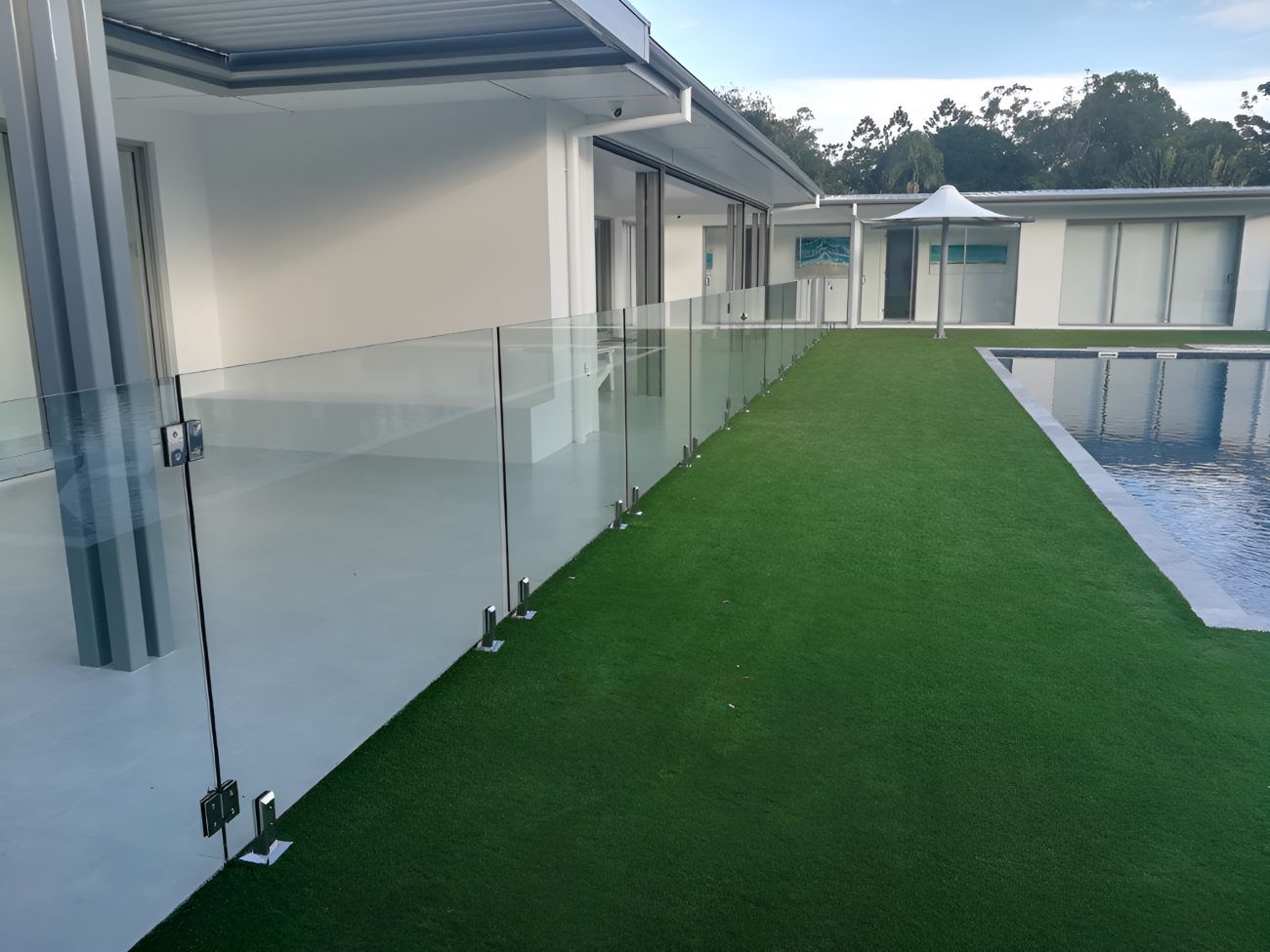 A House With a Swimming Pool and a Glass Fence Around It — Top Shelf Glass Pool Fencing & Balustrading in Helensvale, QLD