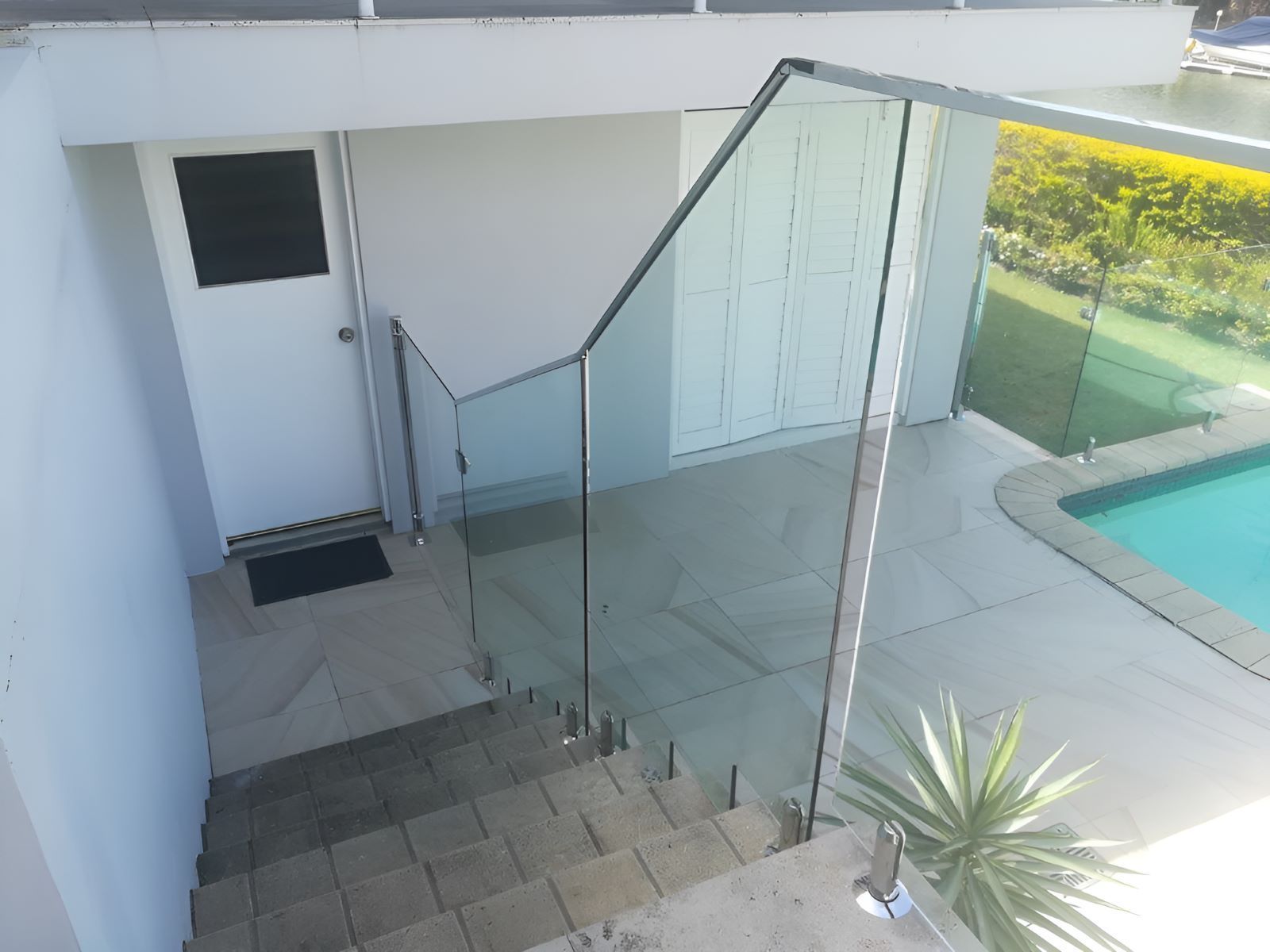 A Staircase With a Glass Railing and a Pool — Top Shelf Glass Pool Fencing & Balustrading in Beenleigh, QLD