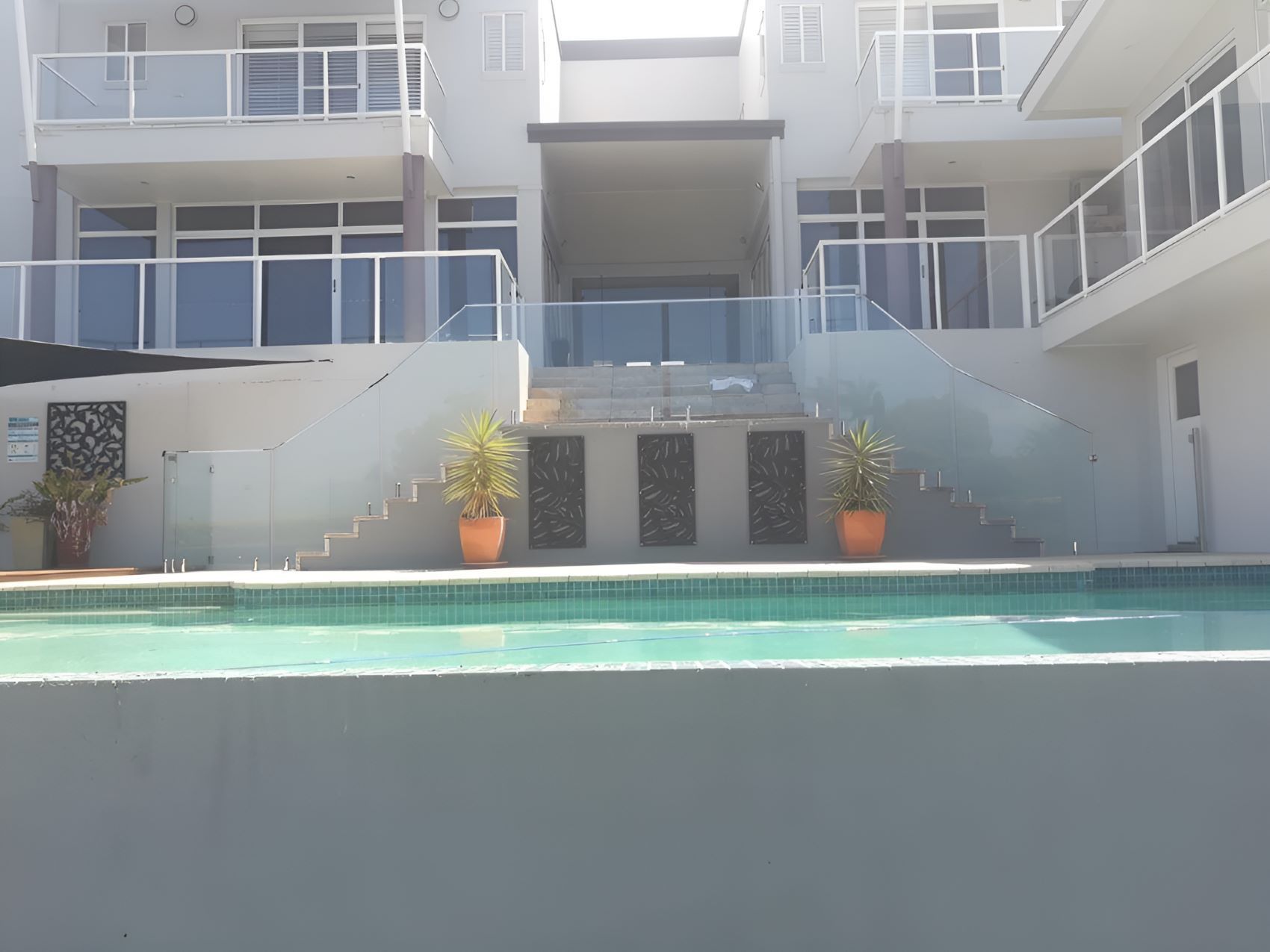 A Large House With a Swimming Pool in Front of It — Top Shelf Glass Pool Fencing & Balustrading in Beenleigh, QLD