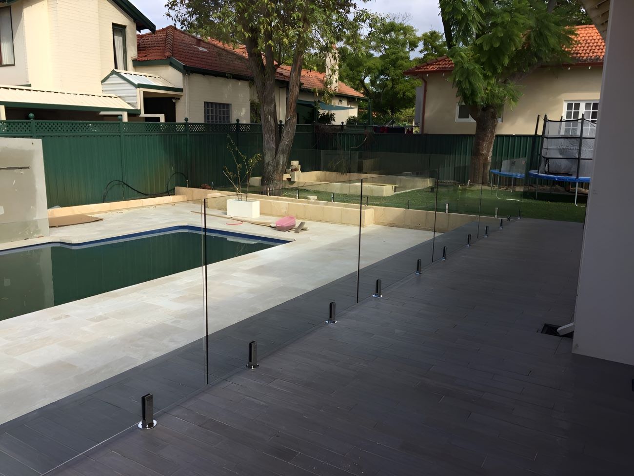 A Swimming Pool is Surrounded by a Glass Fence — Top Shelf Glass Pool Fencing & Balustrading in Brisbane, QLD