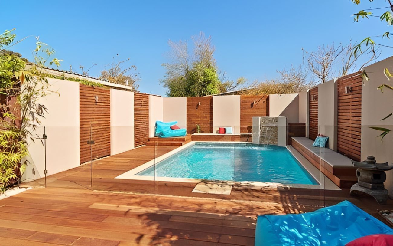 A Swimming Pool in the Backyard With a Wooden Deck — Top Shelf Glass Pool Fencing & Balustrading in Brisbane, QLD