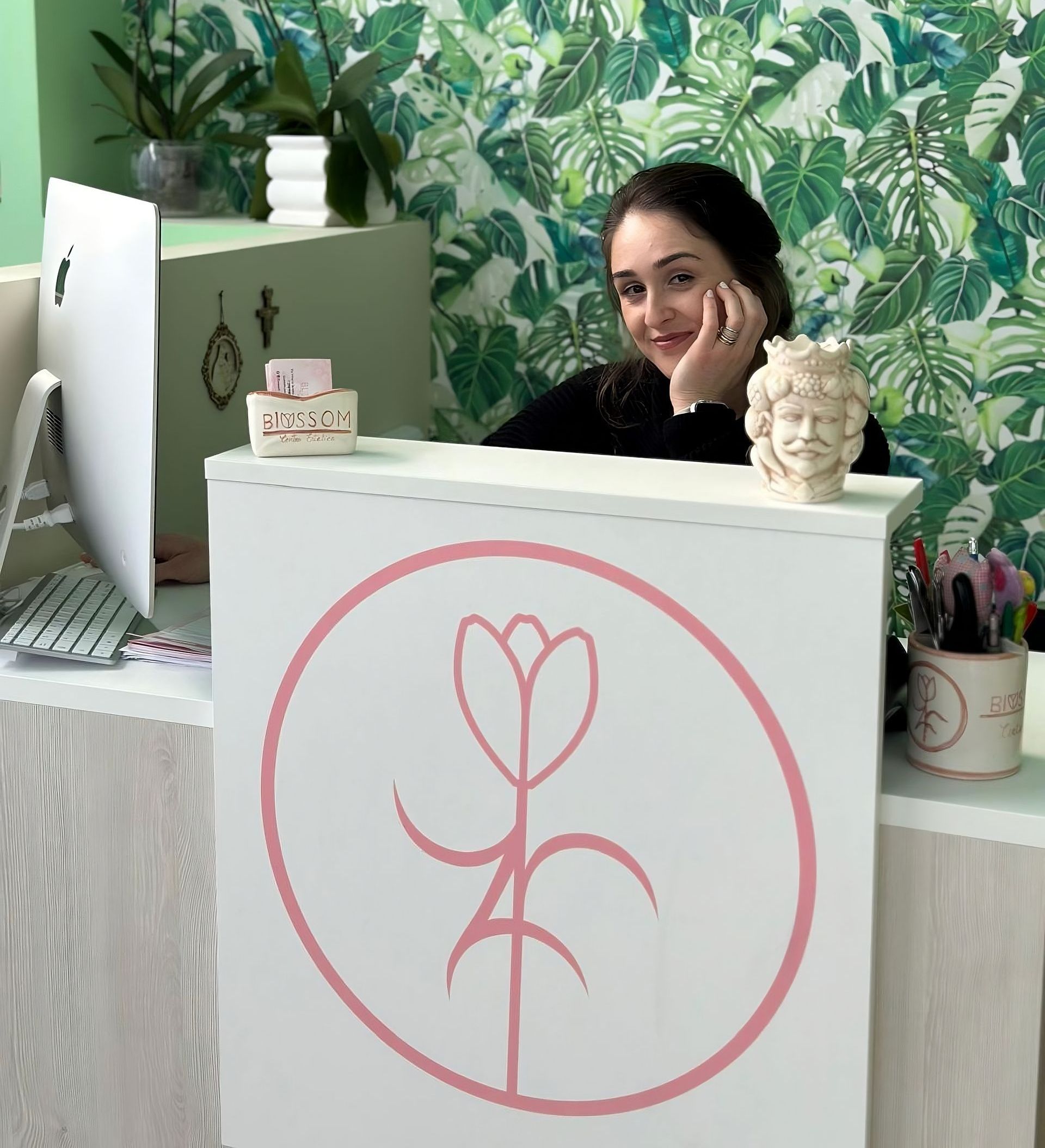 Una donna è seduta a una scrivania con un fiore rosa sopra