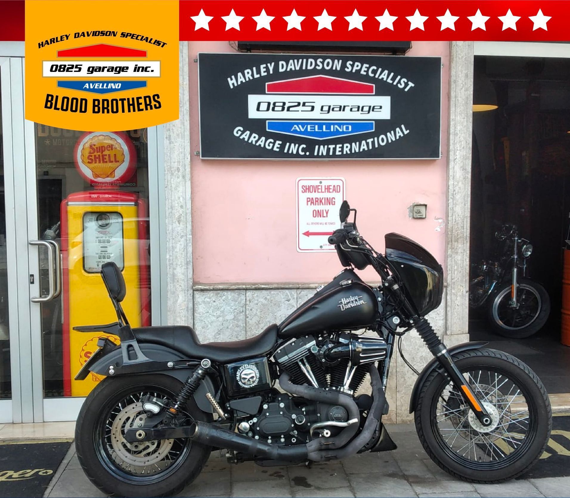 Motocicletta Harley-Davidson nera parcheggiata fuori da un garage. Il garage ha cartelli con la scritta