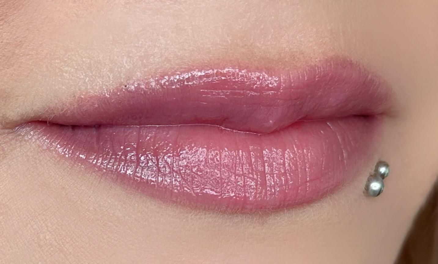 Eine Nahaufnahme der Lippen einer Frau mit Lippenstift und einem Piercing.