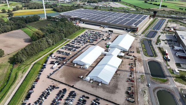 Een luchtfoto van een groot gebouw met veel auto's ervoor geparkeerd