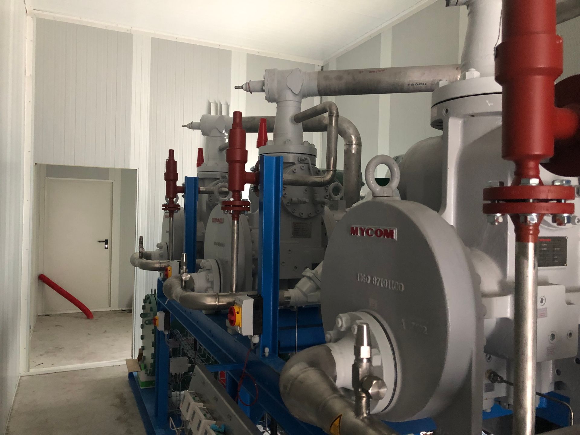 Een kamer met veel leidingen en een machine waarop 'nycom' staat