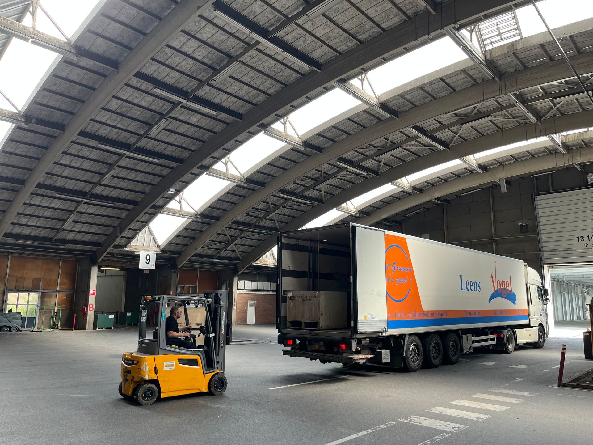 Een vorkheftruck laadt een vrachtwagen in een groot magazijn.