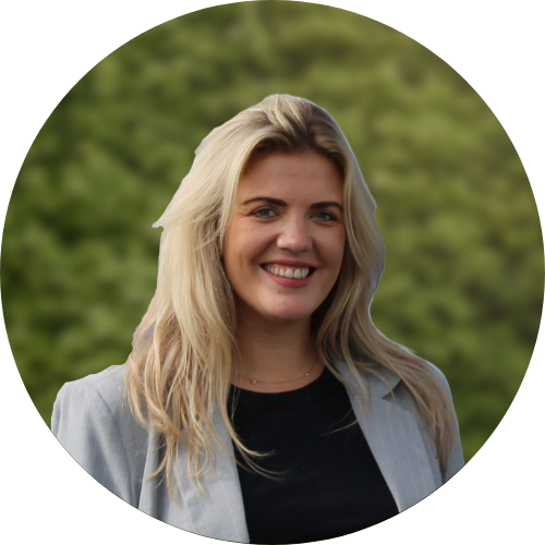 Een vrouw die lacht, ze staat voor een heg