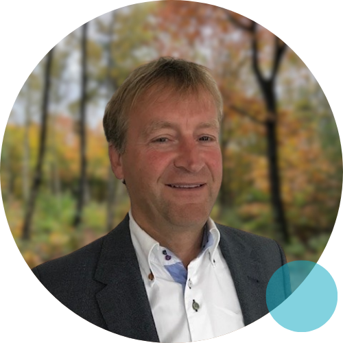 Een man in pak staat lachend in een kring.